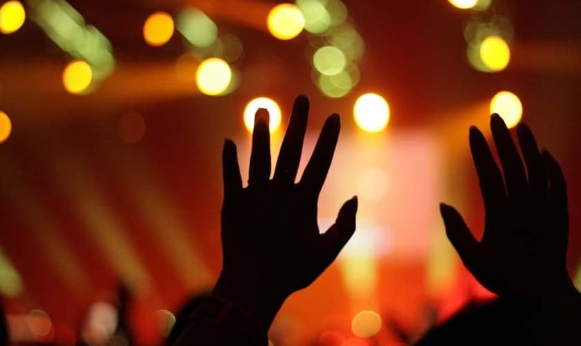 Imagem ilustrativa: mãos levantadas em adoração durante culto.