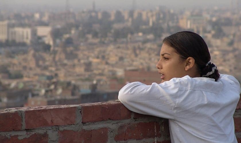 Menina do alto de uma construção olhando a vista do Oriente Médio.