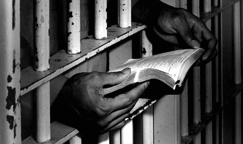 Homem lê bíblia na prisão