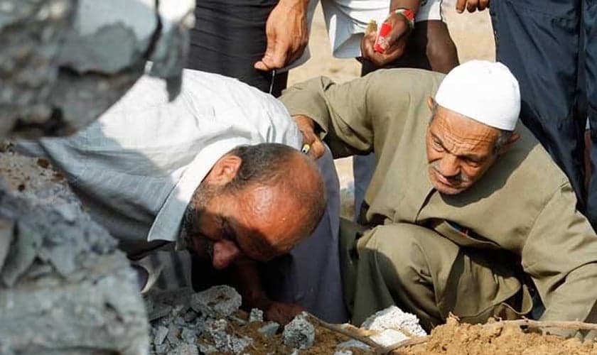 Equipes de resgate palestinas procuram vítimas em um prédio destruído por um ataque aéreo israelense em Rafah.