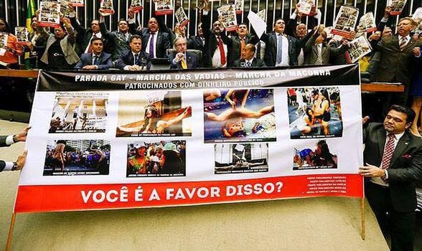 Deputados Evangélicos e católicos expõem cartazes com imagens de protestos que ofenderam o cristianismo, com a profanação de ícones religiosos.