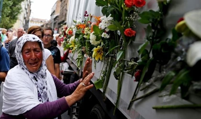 Uma mulher chora ao lado de um caminhão que transportava 136 caixões de recém-identificadas vítimas do massacre de Srebrenica, em 1.995 (Foto: Reuters)