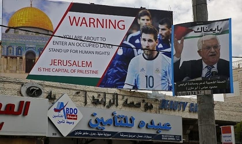 Pôster erguido na Cisjordânia pede boicote a Lionel Messi ao lado do retrato do presidente da Autoridade Palestina, Mahmoud Abbas. (Foto: AFP/Hazem Bader)