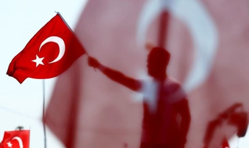 Homem segura bandeira da Turquia durante homenagem aos 'mártires da democracia'. (Foto: Reuters)