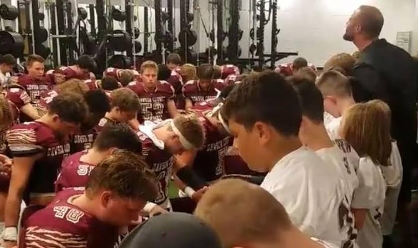 Pastor Russell Davis orando com time de futebol do ensino médio nos Estados Unidos. (Foto: Reprodução)