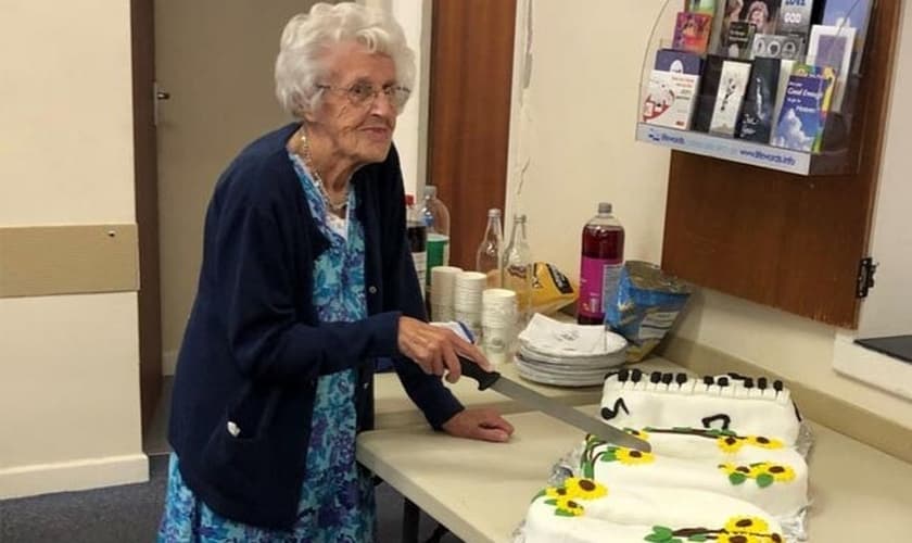 Marion Needham corta o bolo de aniversário preparado em sua homenagem por muitos amigos da igreja para marcar seu 100º aniversário. (Foto: Reprodução/Barnabas Fund)