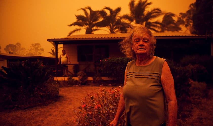 Casal do lado de fora enquanto forte vento empurra a fumaça do incêndio em direção a Nova Gales do Sul, na Austrália. (Foto: Tracey Nearmy/Reuters)