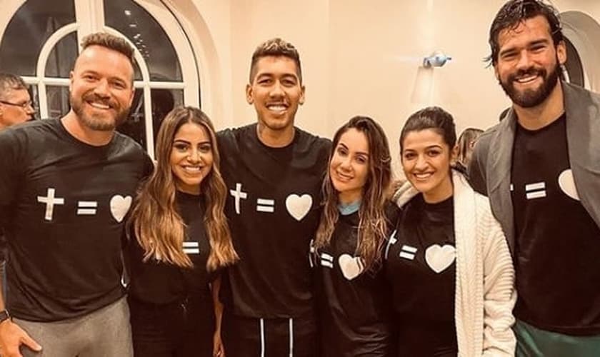 Em seu batismo, Roberto Firmino contou com a presença de sua esposa, Larissa Pereira, do parceiro de time Alisson Becker e da cantora Gabriela Rocha. (Foto: Instagram)