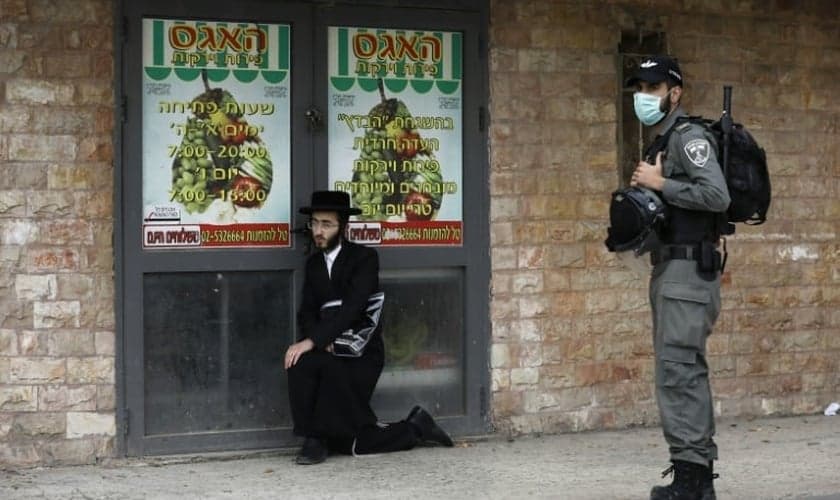 Policial israelense detém um judeu ultraortodoxo durante patrulha em Jerusalém. (Foto: Reprodução/AFP)