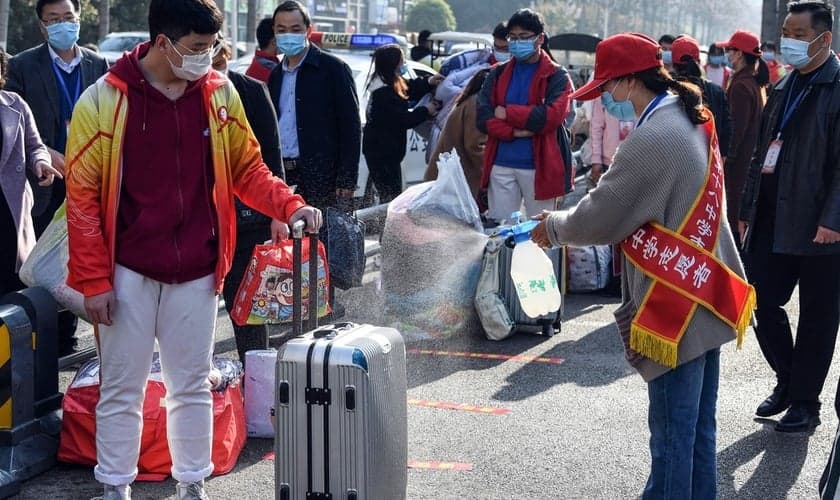 Voluntária aplica desinfetante sobre a bagagem de um aluno em Bozhou, na província de Anhui, no leste da China. (Foto: AFP)