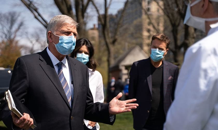 Usando máscaras, Pastor Franklin Graham (esquerda) é acompanhado do cantor Michael W. Smith (ao fundo) durante visita ao hospital de campanha montado pela Samaritan's Purse, organização missionária comandada pelo evangelista. (Foto: Samaritan's Purse)