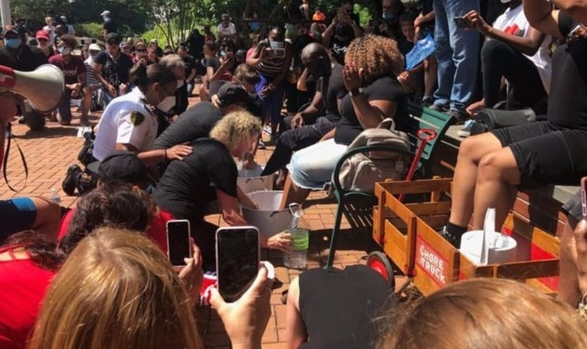 Policiais se sentiram tocados ao ver os líderes cristãos promovendo o momento pacífico de lavar os pés de manifestantes negros, na Carolina do Norte. (Foto: The Sun)
