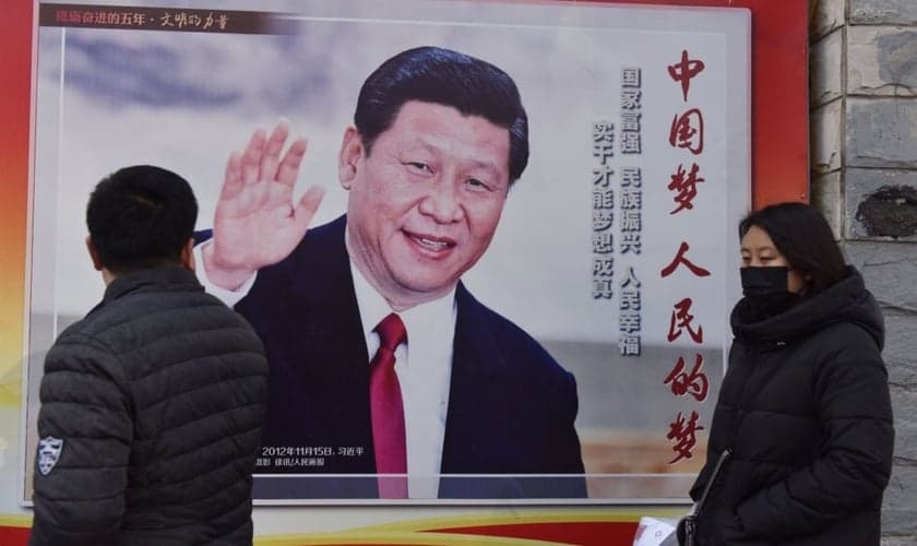 Pessoas passam por um pôster do presidente chinês Xi Jinping ao lado de uma rua em Pequim. O controle cada vez maior de Xi Jinping sobre a China já rendeu ao líder comparações com Mao Tsé Tung. (Foto: AFP / GREG BAKER)