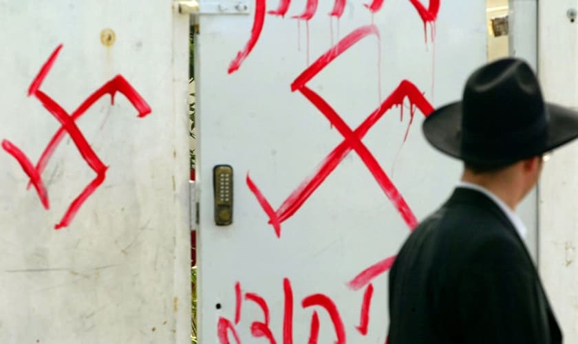 Homem judeu olha para grafite antissemita no portão de uma sinagoga próxima a Tel Aviv, em 2006. (Foto: Uriel Sinai/Getty Images)