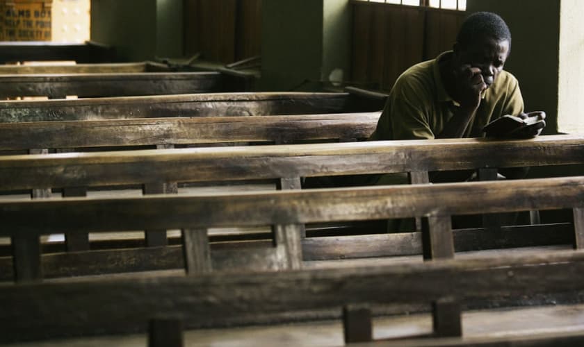 Cristão lê Bíblia sozinho no banco de uma igreja em, Kano, Nigéria. (Foto: Getty Images/Chris Hondros)
