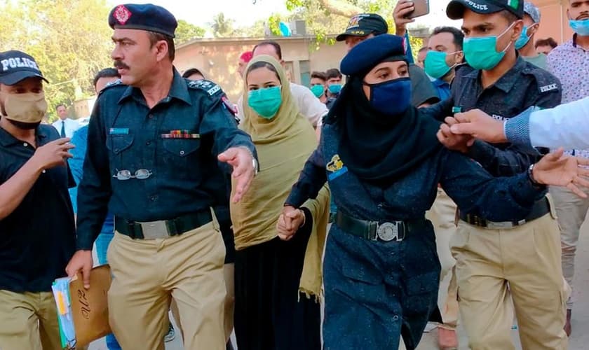 Policiais escoltam a adolescente paquistanesa Arzoo Raja, após sua aparição no Tribunal Superior de Sindh, em Karachi, Paquistão, no dia 3 de novembro de 2020. (Foto: AP Photo/Fareed Khan)
