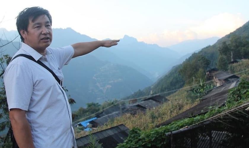 O pregador Pu Zhidui apontando para igreja, duas montanhas adiante, que ele está pastoreando. (Foto: Bible Society).