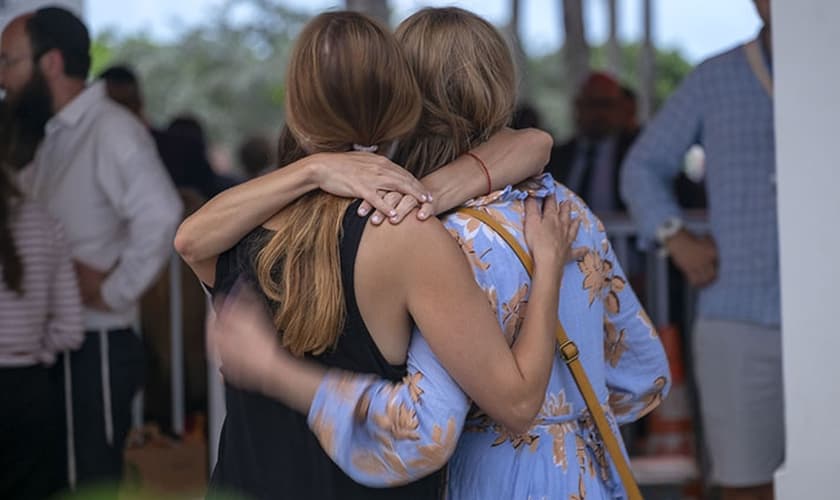 Depois de ouvir a notícia do colapso do prédio do condomínio, os moradores se agarram uns aos outros em Miami, EUA. (Foto: Billy Graham Association).