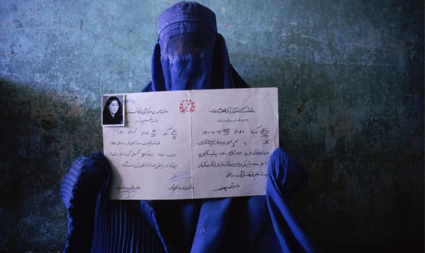 Mulher segura seu diploma de quando estudava, antes da tomada do poder pelo Talibã. (Foto: Nina Berman/NOOR)