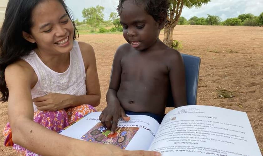 Rachel lendo o livro de sua autoria “Adotados em Amor” para uma criança Yolngu. (Foto: Reprodução/Eternity)