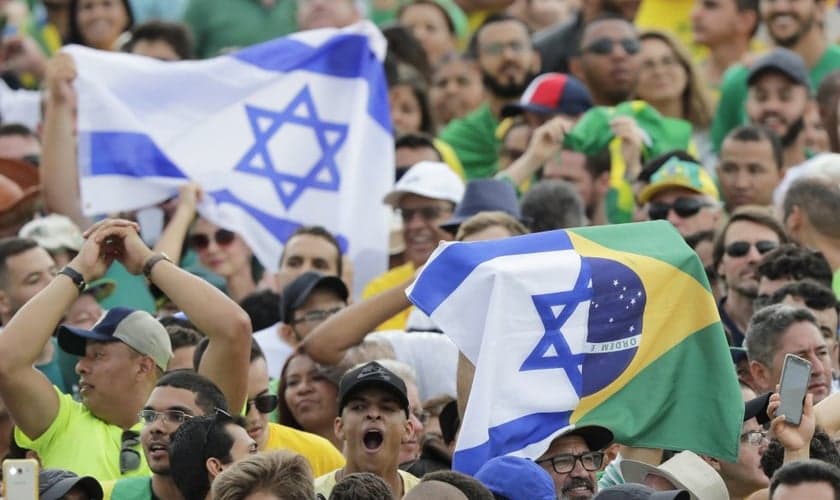 Brasileiros seguram a bandeira de Israel. (Foto: Silvia Izquierdo/AP)