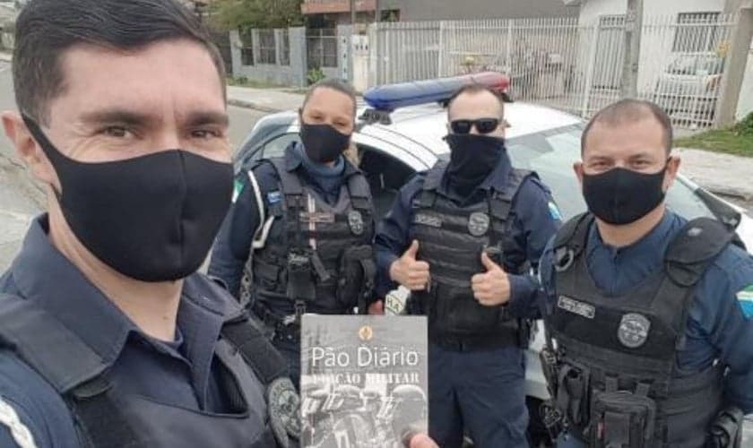 Imagem representativa de policiais segurando exemplares. (Foto: Pão Diário/Facebook)