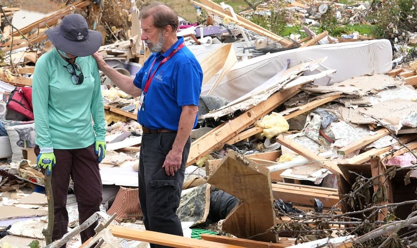 Um capelão orando com uma mulher que perdeu tudo após um tornado. (Foto: Reprodução/BGEA)