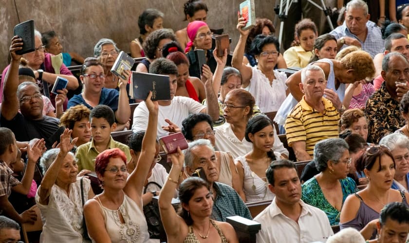 Evangélicos de uma igreja cubana erguem suas Bíblias durante o culto. (Foto: IMB)